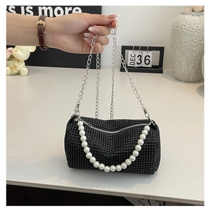 Détail du sac cylindre à strass noirs avec chaîne de perles et bandoulière argentée