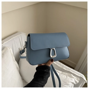 Close-up of matte dusty blue leather crossbody bag with elegant silver U-shaped metal lock