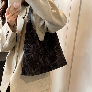 Chic black underarm bag with bamboo leaf pattern on model with beige blazer