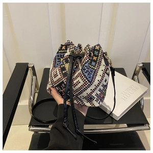 Detail of woven bucket bag with geometric patterns, drawstring closure and golden rings