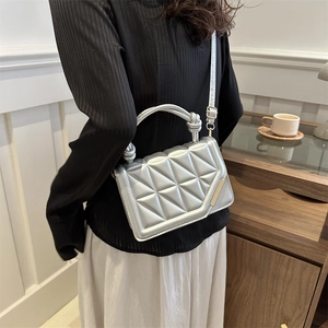 Silver quilted crossbody bag with knot handle worn by model in a casual cafe setting