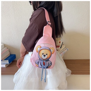 Pink kids crossbody bag featuring a cartoon bear print worn by a child in home setting
