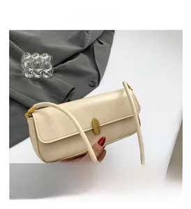 Detailed view of beige faux leather baguette bag with elegant golden oval metal twist lock
