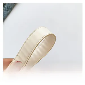 Détail de la bandoulière en cuir crème avec des coutures blanches et une texture lisse