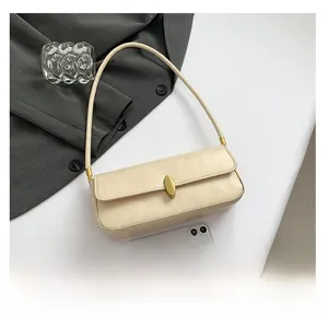 Detail of off-white baguette bag featuring a gold oval clasp and textured leather