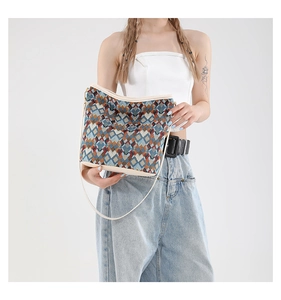 Gros plan du motif jacquard géométrique et de la bandoulière en cuir crème du sac seau