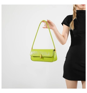 Detail shot of green metallic baguette bag with gold buckle and textured leather strap
