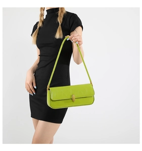 Detail of lime green glossy leather shoulder bag with gold metal buckle on model