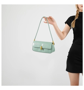Detail of light green glossy underarm bag featuring a vintage golden oval metal clasp