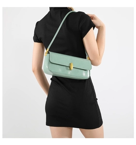 Close-up of light green minimalist underarm bag with gold metal buckle on model