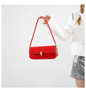 Close-up of red glossy baguette bag featuring an elegant gold oval metal buckle detail
