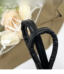 Close-up of black leather bag with stylish scrunchie handle and soft pleated texture