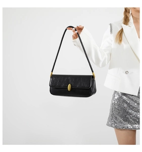 Detail of minimalist black baguette bag with glossy wrinkled texture and golden clasp