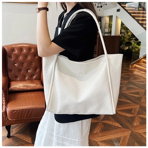 Close-up of white woven leather texture on a large minimalist tote bag on a sofa