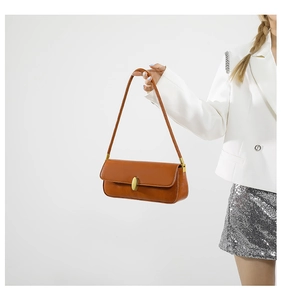 Detail of a brown leather baguette bag featuring a gold oval clasp and sleek shoulder strap
