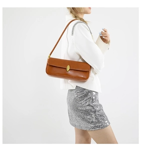 Close-up of caramel brown leather shoulder bag with elegant oval gold metal buckle detail