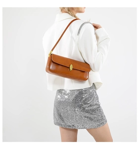 Detail view of caramel brown faux leather baguette bag with gold magnetic buckle
