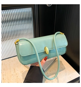 Close-up of mint green leather baguette bag with a stylish gold oval metal buckle