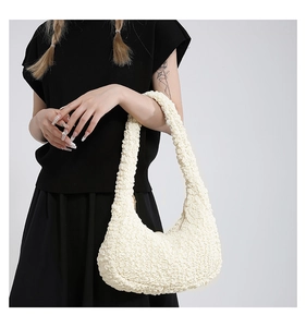 Dettaglio del tessuto beige a bolle e della forma a mezzaluna di questa borsa a spalla