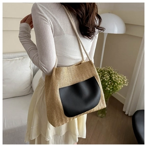 Détail d'un sac cabas en paille tissée avec une poche avant en cuir noir contrasté