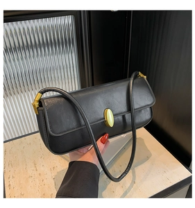 Detail of a black leather baguette bag with a premium golden oval metal buckle closure