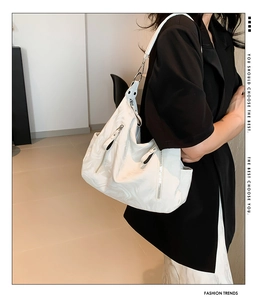 Detail of white marble textured slouchy shoulder bag with silver hardware on model