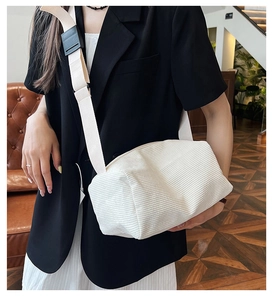 Close-up of white corduroy crossbody pillow bag with wide adjustable shoulder strap