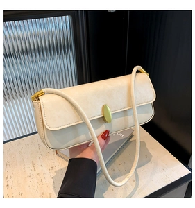 Detail of creamy white faux leather baguette bag with a polished gold magnetic buckle