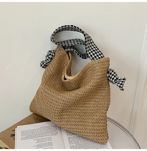 Detailed close-up of woven straw tote bag featuring a stylish houndstooth fabric shoulder strap