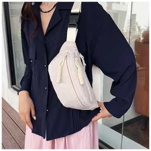 Détail d'un sac bandoulière blanc cassé avec large sangle et boucle de fermeture noire