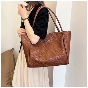 Close-up of the intricate hand-woven brown leather texture on a spacious tote bag