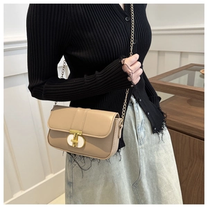 Beige chain square bag with gold buckle lock shown on model as a stylish crossbody