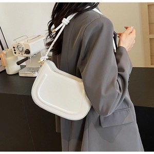 Detail of white half-moon underarm bag featuring U-shaped texture and braided strap
