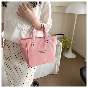 Detail of pink canvas tote showing durable straps, rivet accents and fashion lettering