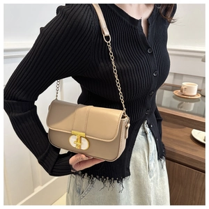 Detail of khaki square shoulder bag with metal T-shaped buckle and chain strap on model