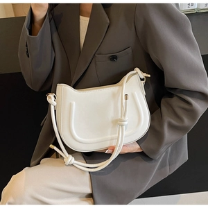 Detailed view of white underarm bag with unique U-shaped stitching and knotted rope strap