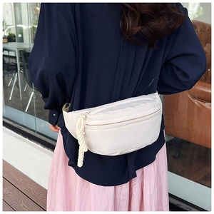 Détail d'un sac banane en nylon beige avec poches zippées et tirette en corde tressée