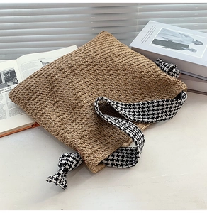 Close-up of woven straw bag with stylish houndstooth strap and decorative knot detail