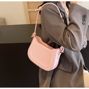 Detailed side view of a pink underarm bag with knot detail and gold hardware on a model