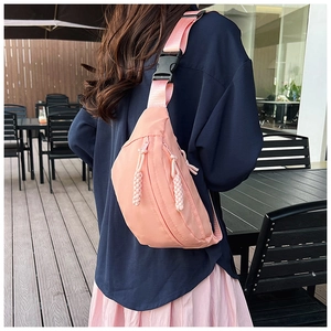 Sac banane rose en nylon avec sangle réglable porté dans un café en plein air