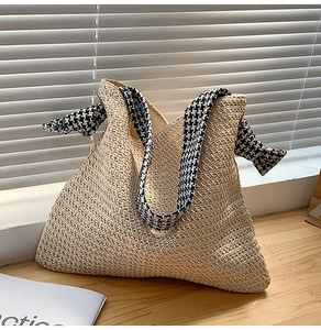 Detail of V-shaped straw weave texture and houndstooth fabric strap on beige tote