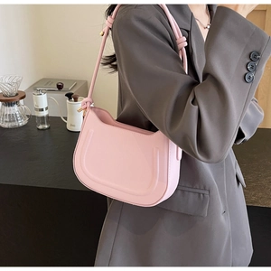 Detail of pink half-moon shoulder bag featuring a unique knot design on the strap