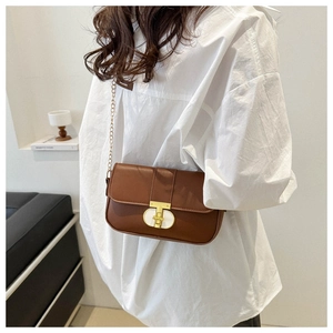 Detail of brown leather handbag featuring a golden T-shaped metal clasp and chain strap