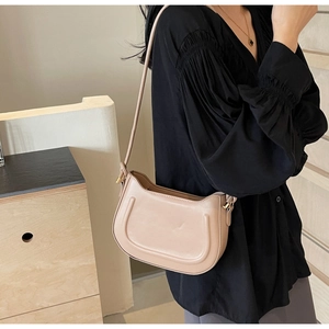 Detailed view of beige minimalist underarm bag featuring curved lines on matte leather