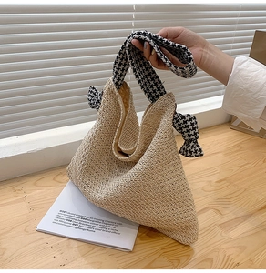 Detail der handgeflochtenen Strohtasche mit schwarz-weißem Hahnentritt-Stoffgriff und Knoten