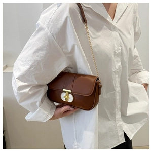 Brown leather square bag detail with gold chain strap shown on a model side view