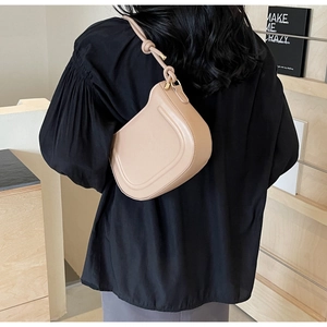 Detail of beige crescent underarm bag showing textured faux leather and knotted strap