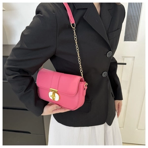 Close-up of bright magenta crossbody bag featuring a golden T-shaped twist lock closure