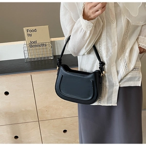 Detail of black leather saddle bag featuring unique embossed U-shape and knot shoulder strap