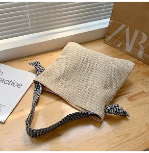 Detail of woven straw tote bag with black and white houndstooth knotted shoulder strap